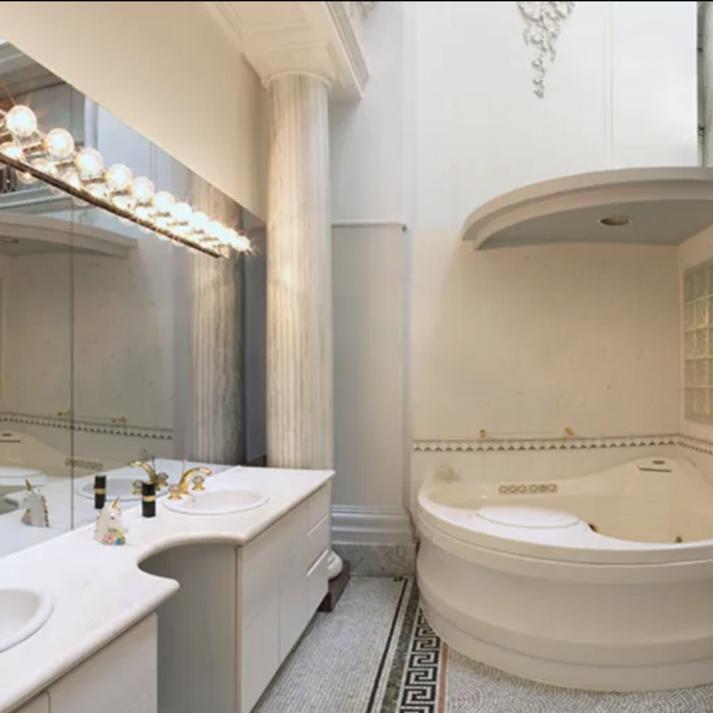 A spacious bathroom featuring a curved white vanity, an oval whirlpool tub, and luxurious accents.