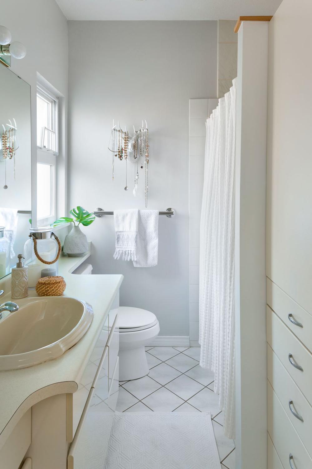 A clean and minimalist modern bathroom with soft gray walls and subtle decor accents.