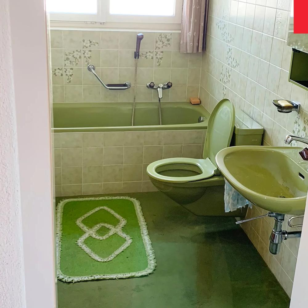 A vintage bathroom with various shades of monochromatic green, including fixtures and accessories.
