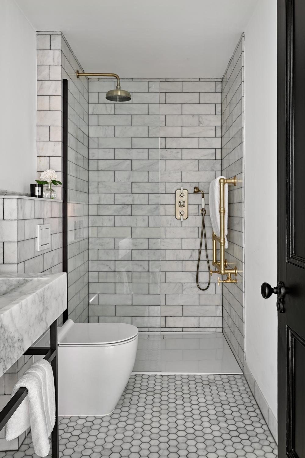 Sleek white subway tiles enhanced by elegant gold accents in a modern shower.