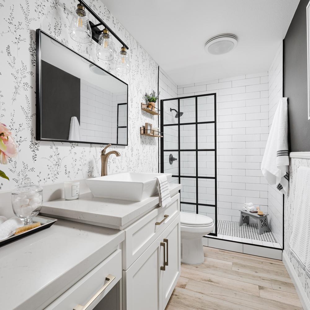 A modern bathroom with black grid shower design, elegant lighting, and chic vainities complemented by floral wallpapers adding character.