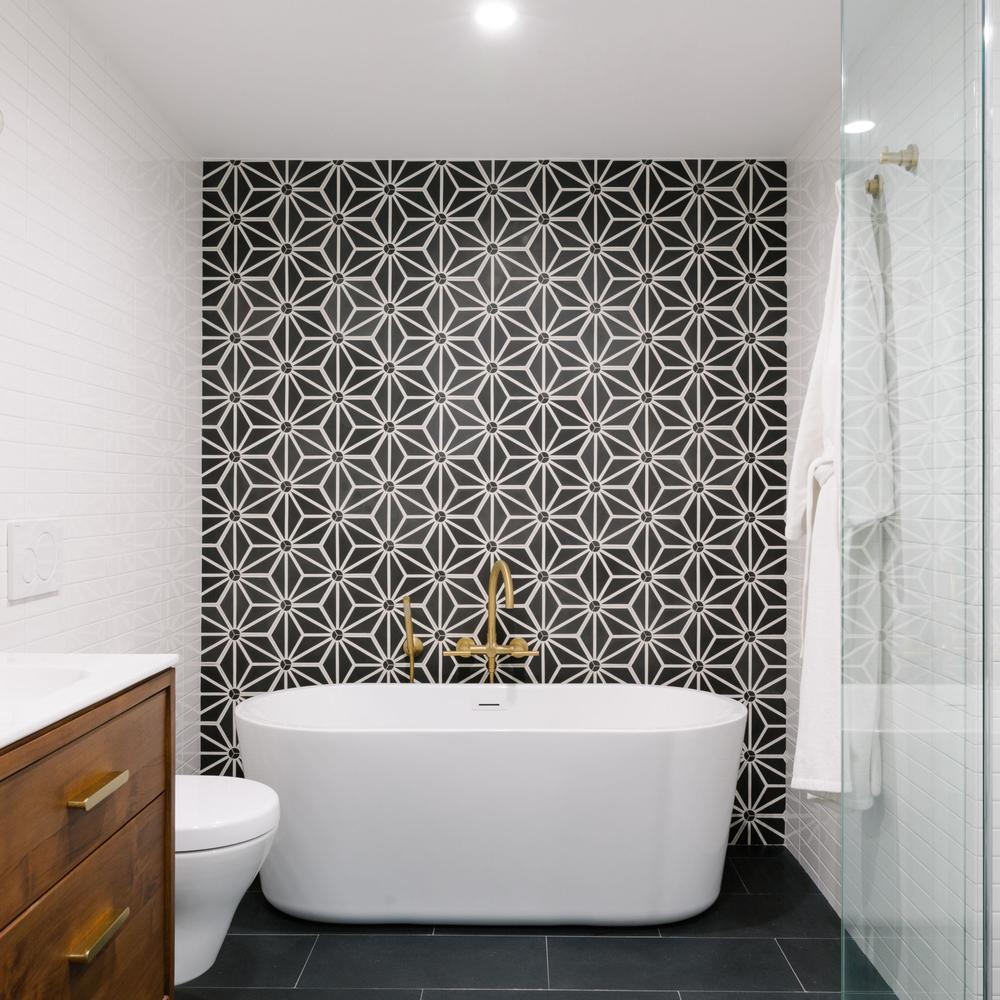 A spacious bathroom featuring a visually striking black accent wall, luxurious freestanding tub, and earthy decor adding a touch of nature to the overall design.