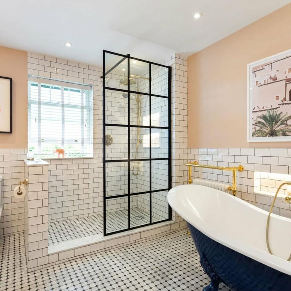 Baño elegante con azulejos blancos y pared de acento color durazno.