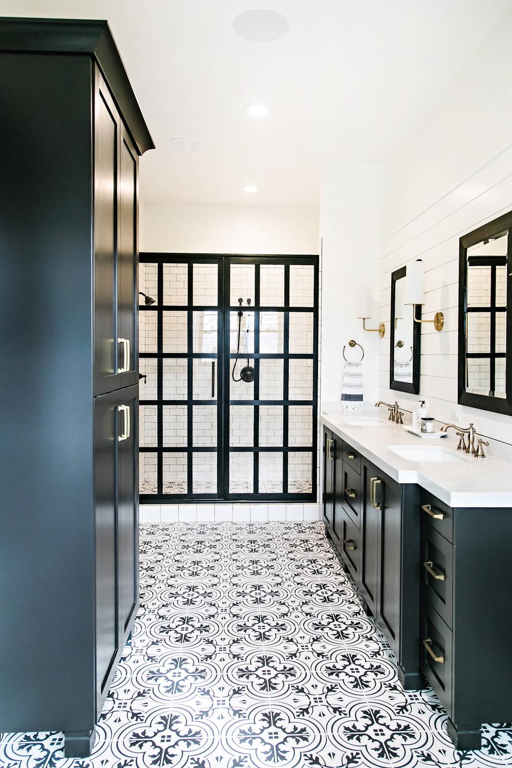 A modern American farmhouse bathroom showcasing sleek black cabinets and a glass shower enclosure with black grid accents.