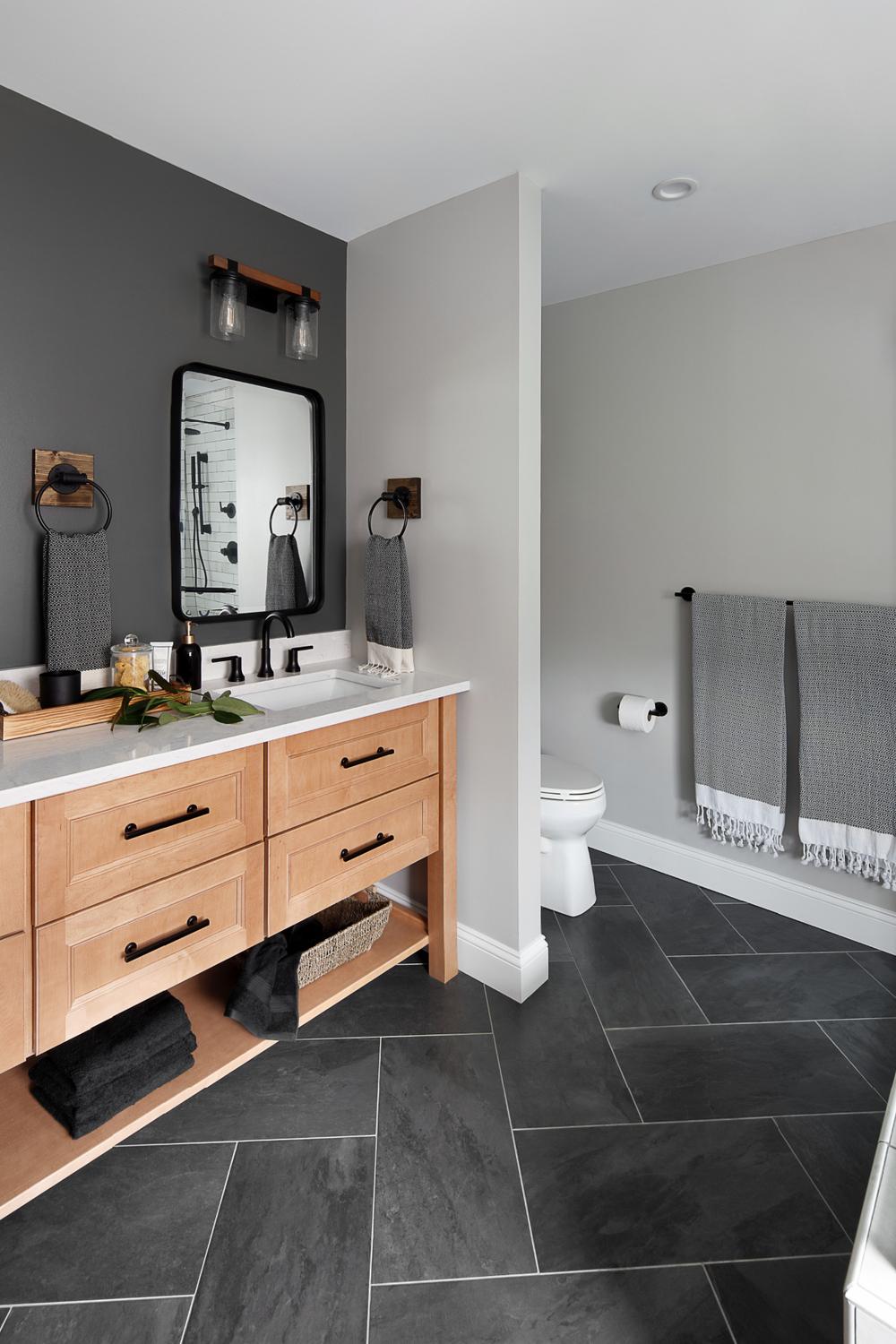 Artistic American farmhouse bathroom with black cabinets and functional designs.