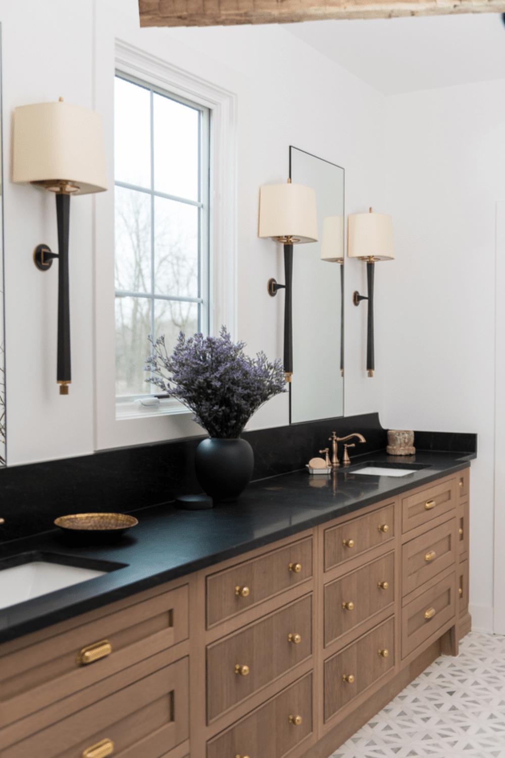 Luxurious American farmhouse bathroom showcasing dual vessel sinks and black cabinetry.
