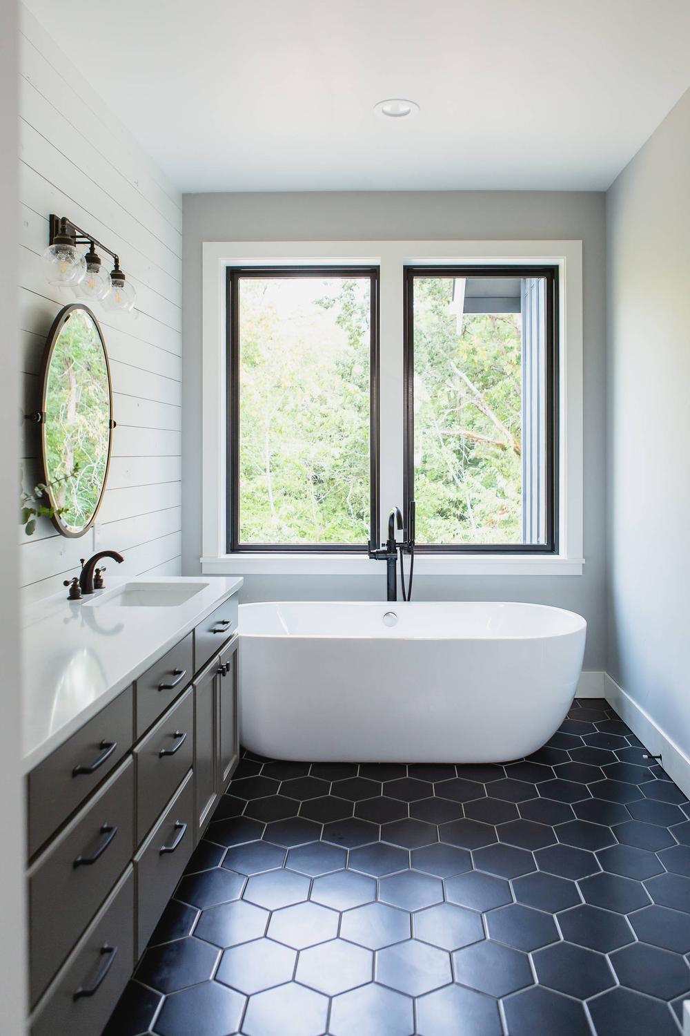 Elegantly designed American farmhouse bathroom with natural textures and black cabinetry.