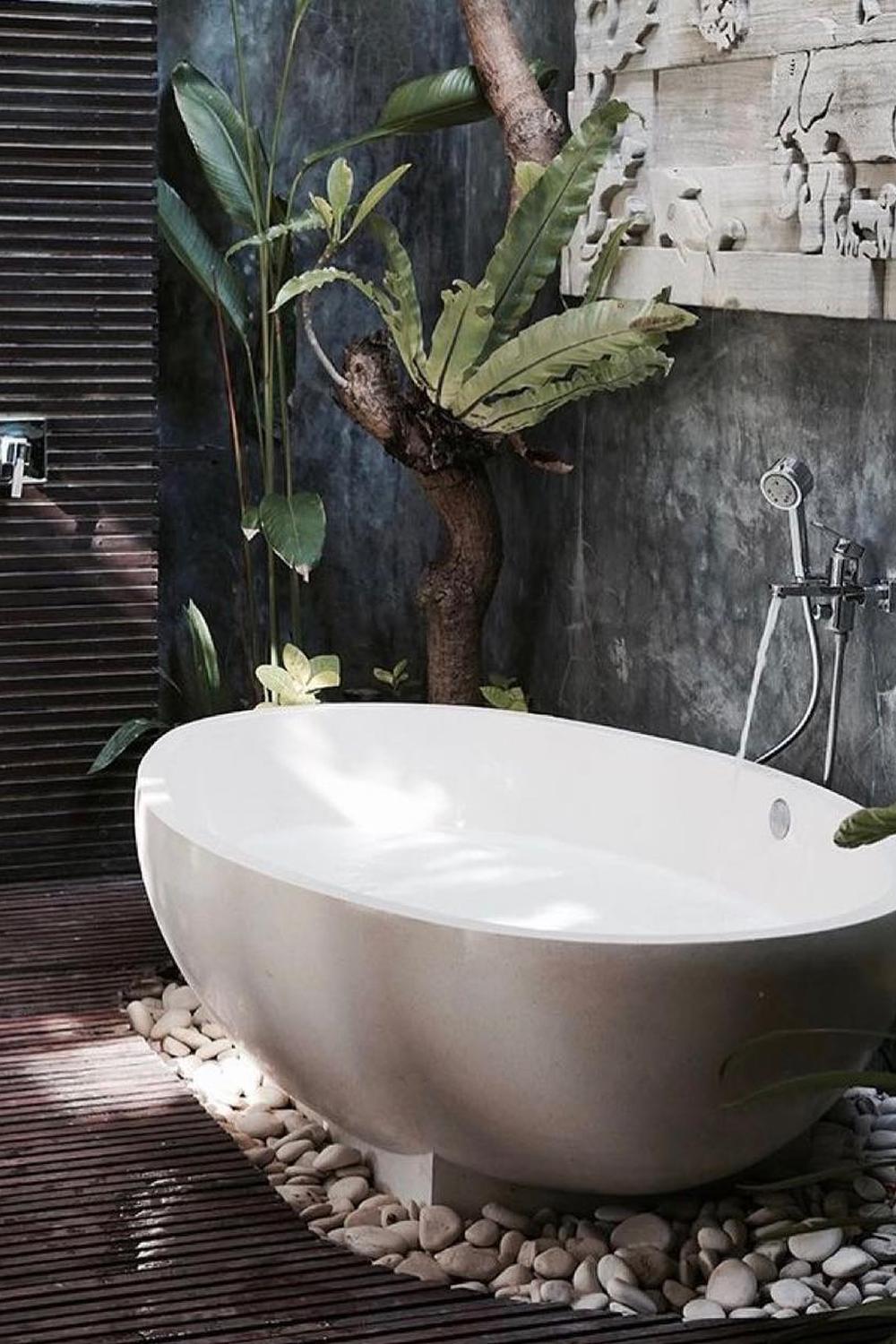 Baño al estilo Bali con bañera exenta ovalada y decoración natural