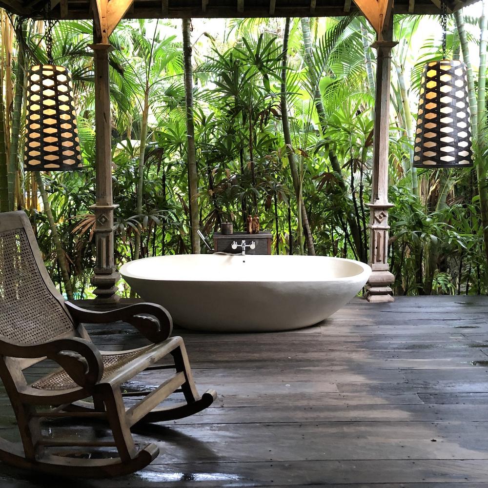 Baño abierto con bañera ovalada y rodeado de vegetación