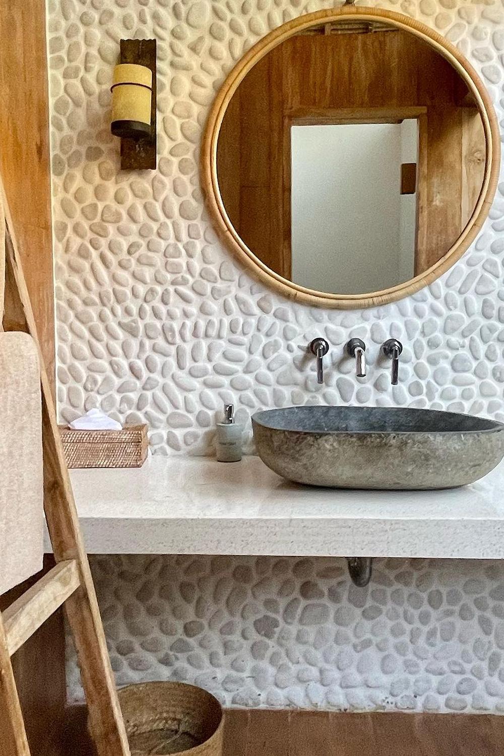 Baño con pared de piedras y lavabo de piedra redonda