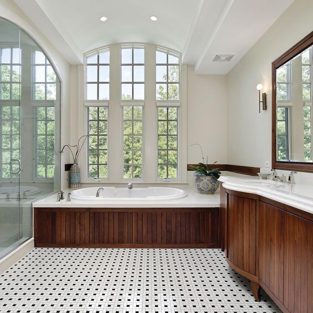 Bathroom with large arched windows allowing natural light into the basketweave tile space.