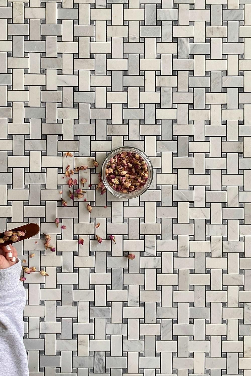 Close-up of basketweave tile design and decorative storage solutions in a bathroom.