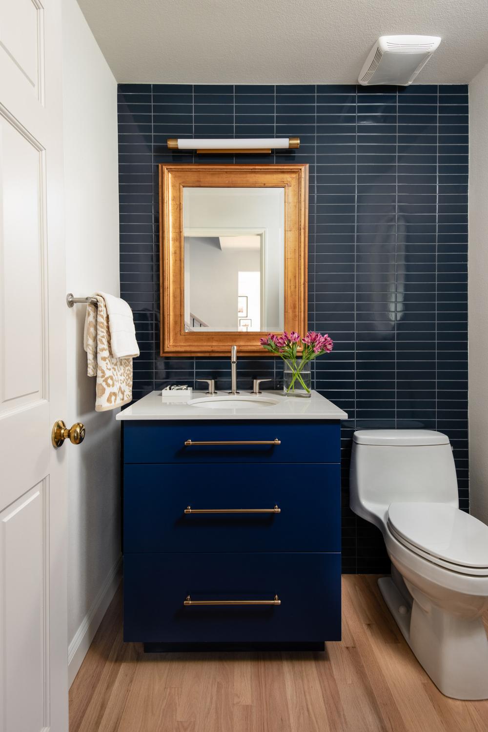 Baño elegante con acento azul oscuro y espejos enmarcados en madera