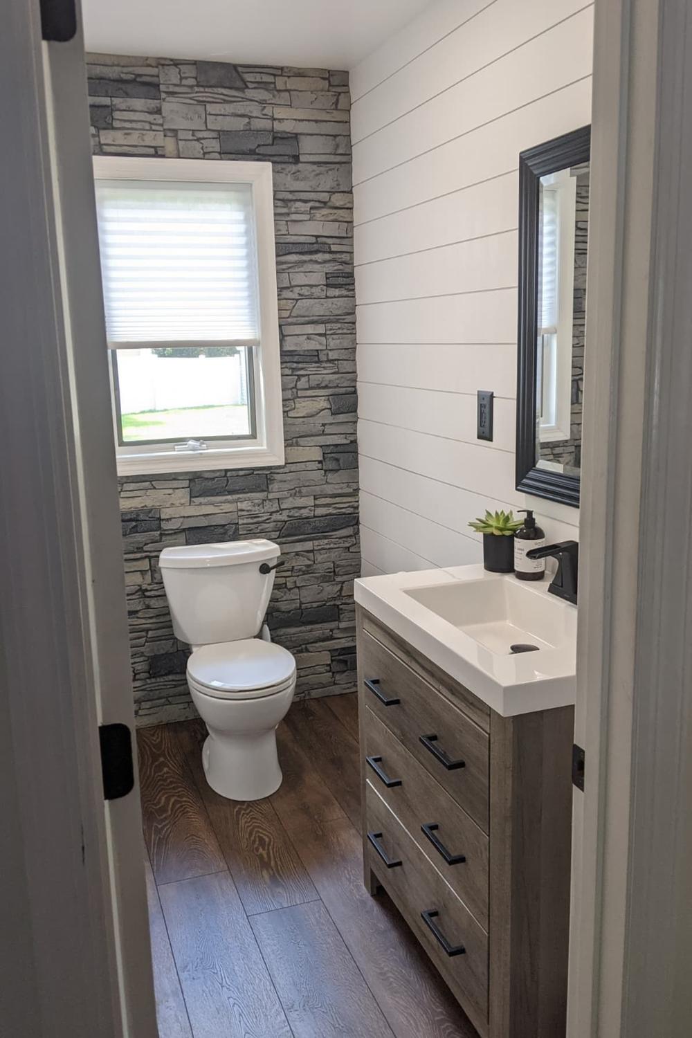 Baño natural con acento de piedra oscura y paneles de madera clara