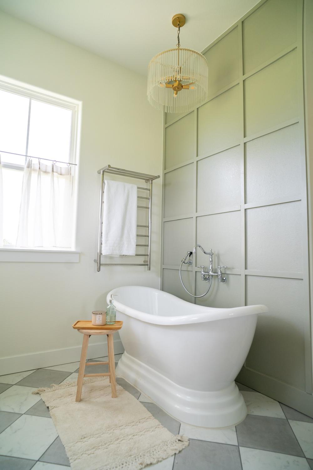 Baño minimalista con acento en verde suave y bañera independiente