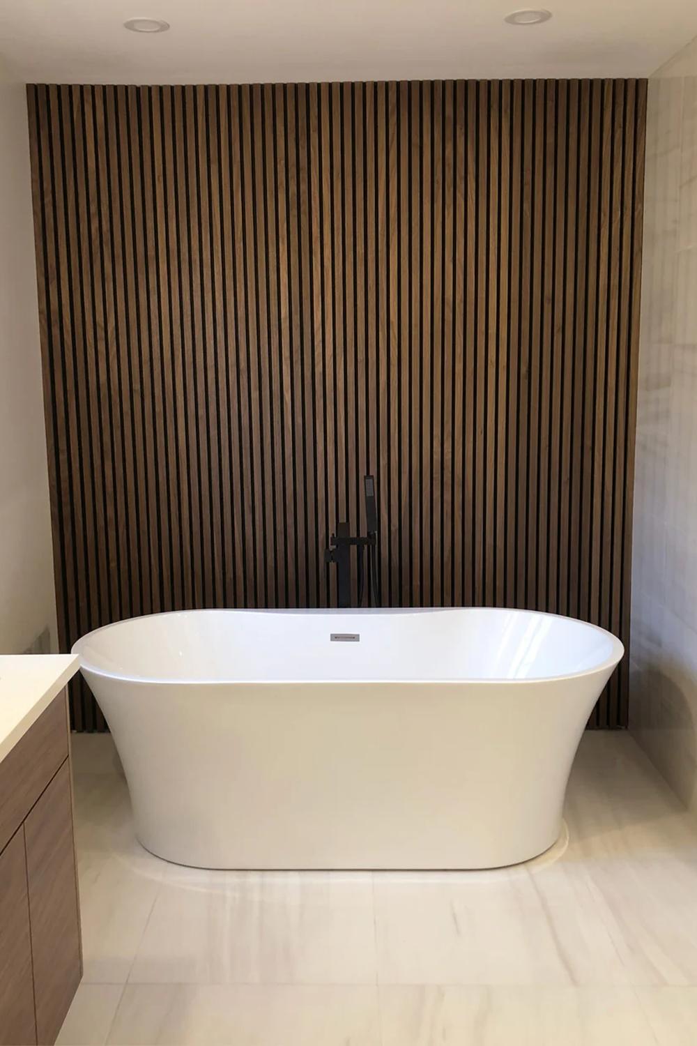 Baño relajante con acento de madera vertical y bañera independiente