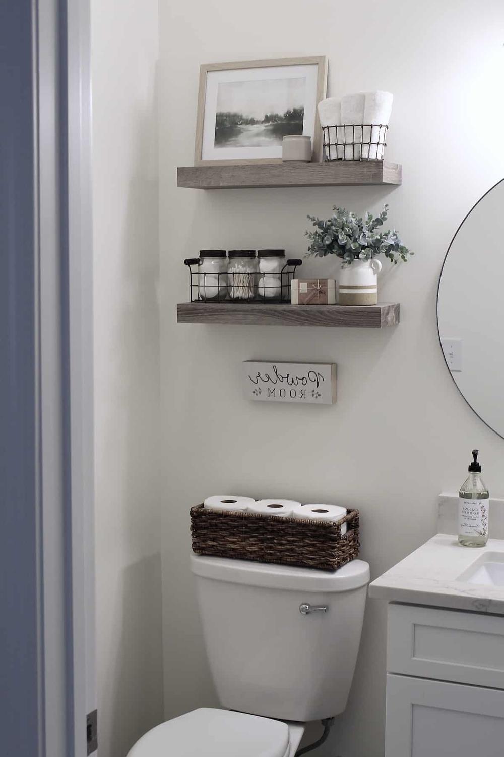 Estanterías de madera clara decoradas con fotos y plantas sobre un inodoro.