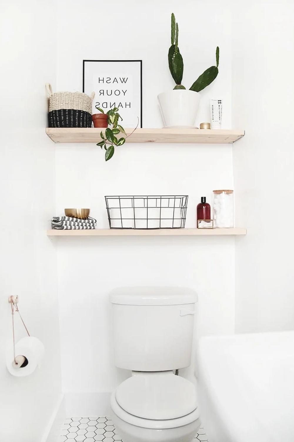 Estanterías blancas simples sobre el inodoro en un baño zen.