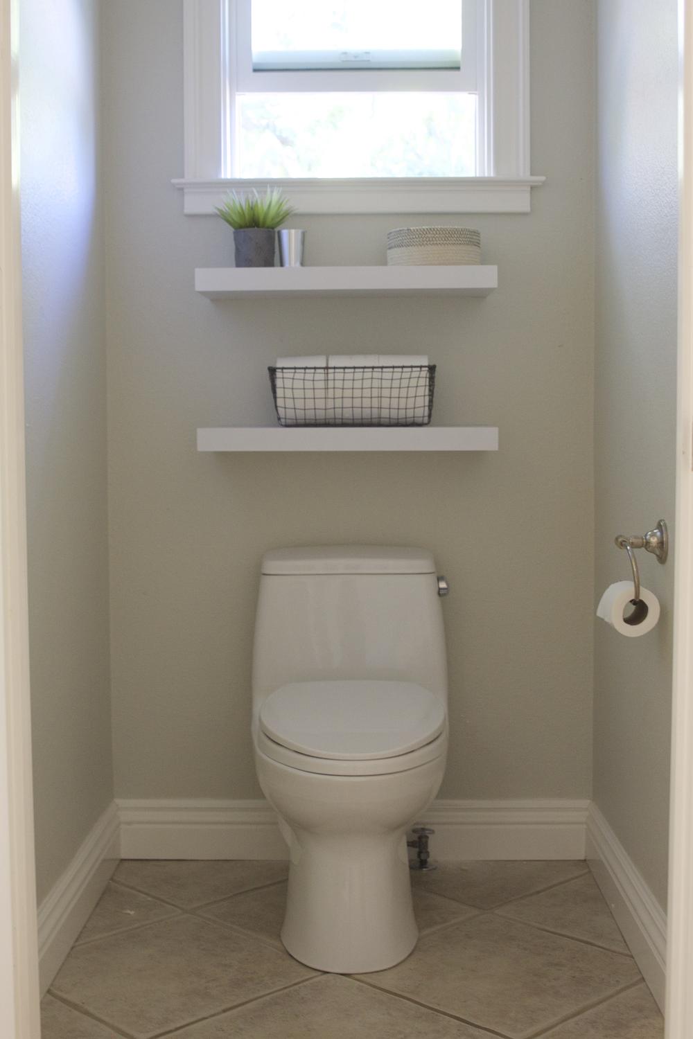 Estanterías flotantes sobre un inodoro con plantas decorativas.