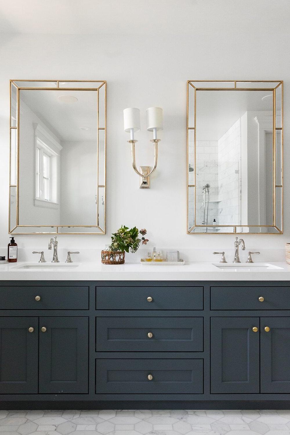 Contemporary bathroom featuring gold-hued rectangular mirrors with matching sconces.