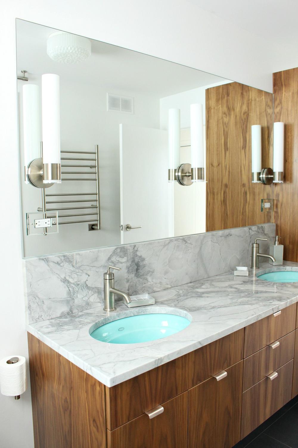 Modern frameless mirror complemented by stylish sconces in a contemporary bathroom.