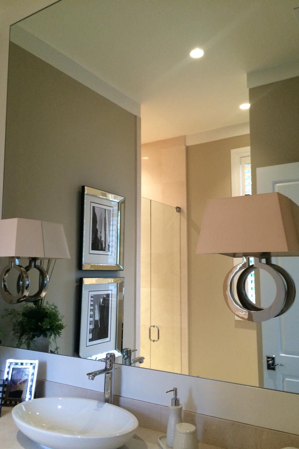 Stylish bathroom featuring a large round mirror with elegant sconces on either side.