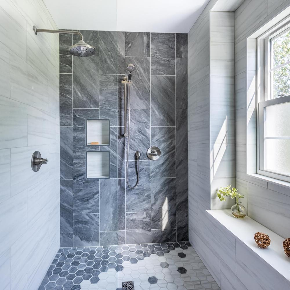 A shower featuring textured light grey and dark grey tiles for a contemporary aesthetic