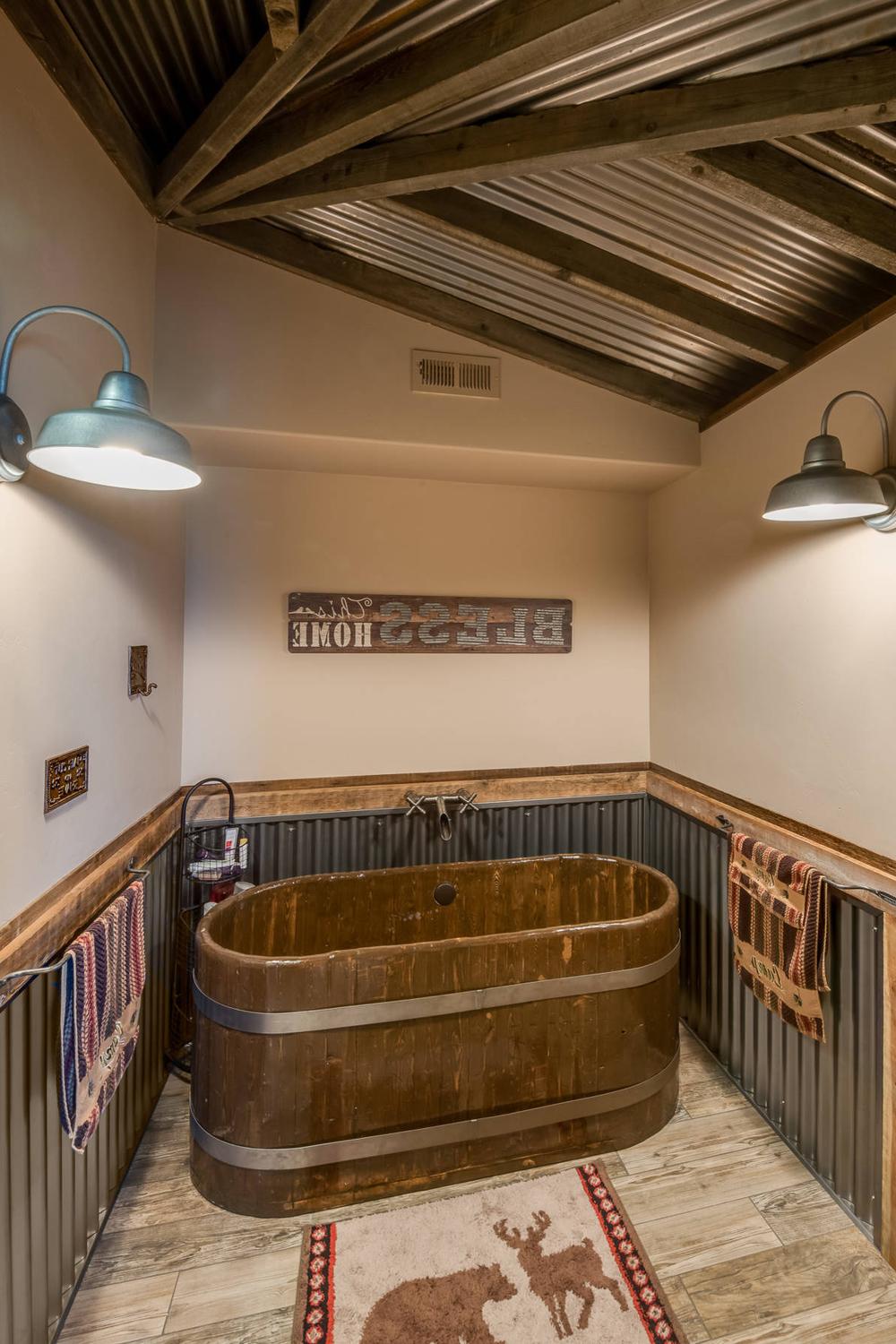 Baño con bañera de madera y elementos de lata