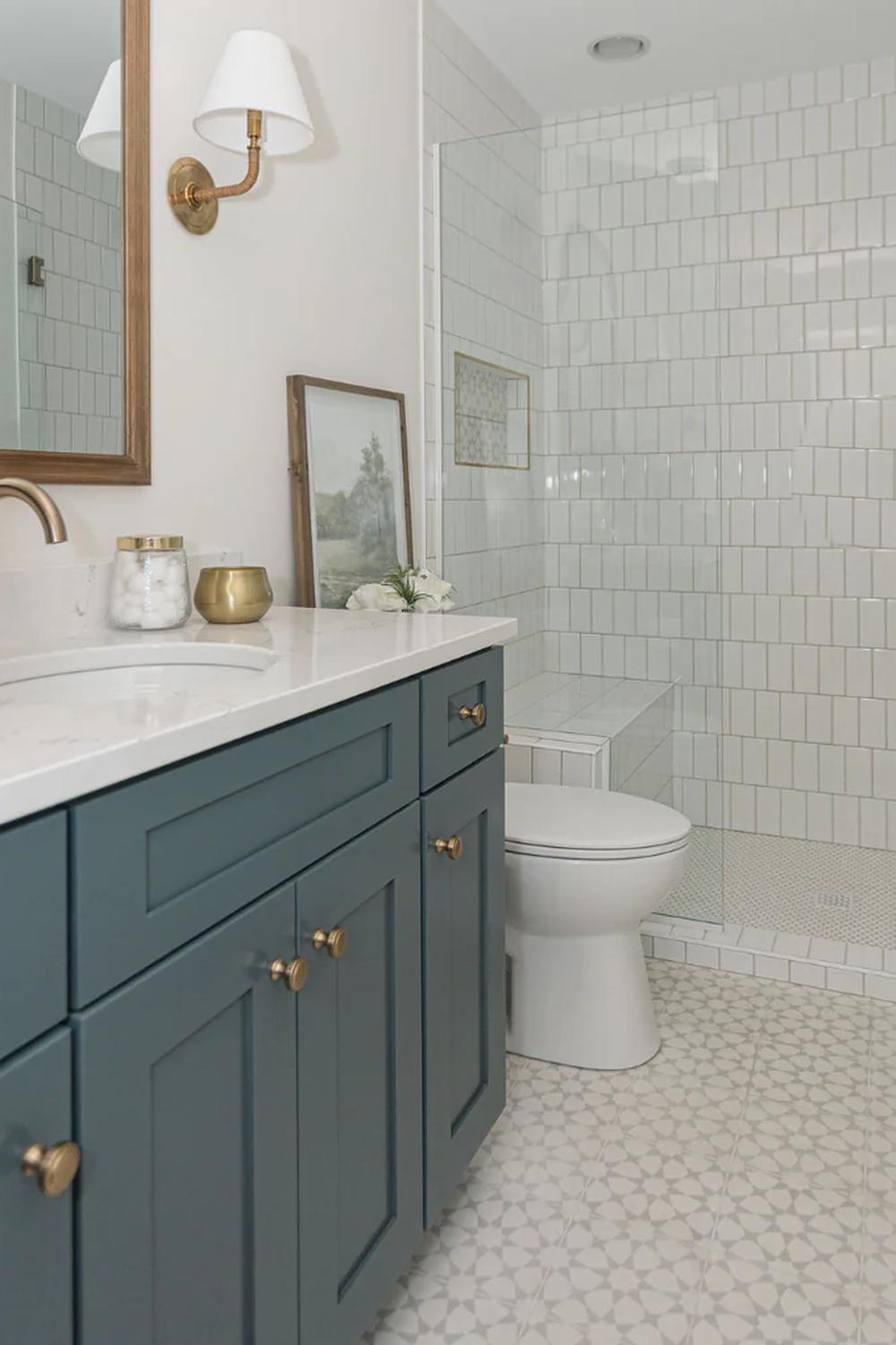 Deep teal bathroom vanity with brass handles and white marble countertop, exuding a luxurious atmosphere.