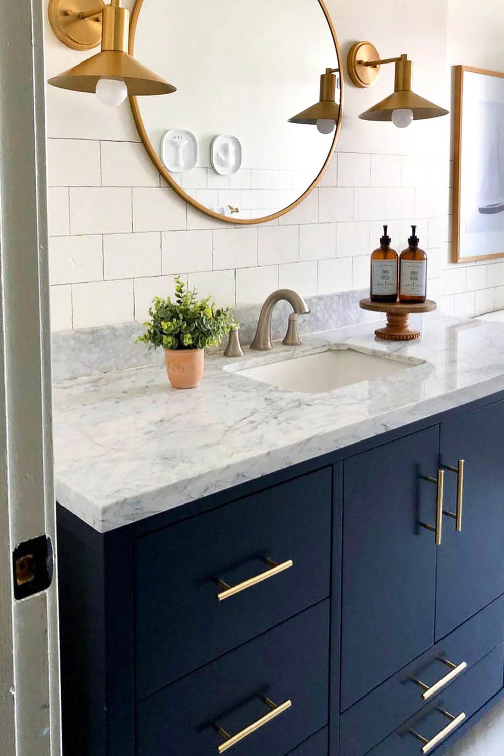 Navy blue bathroom vanity contrasted with a luxurious marble countertop and gold accents.