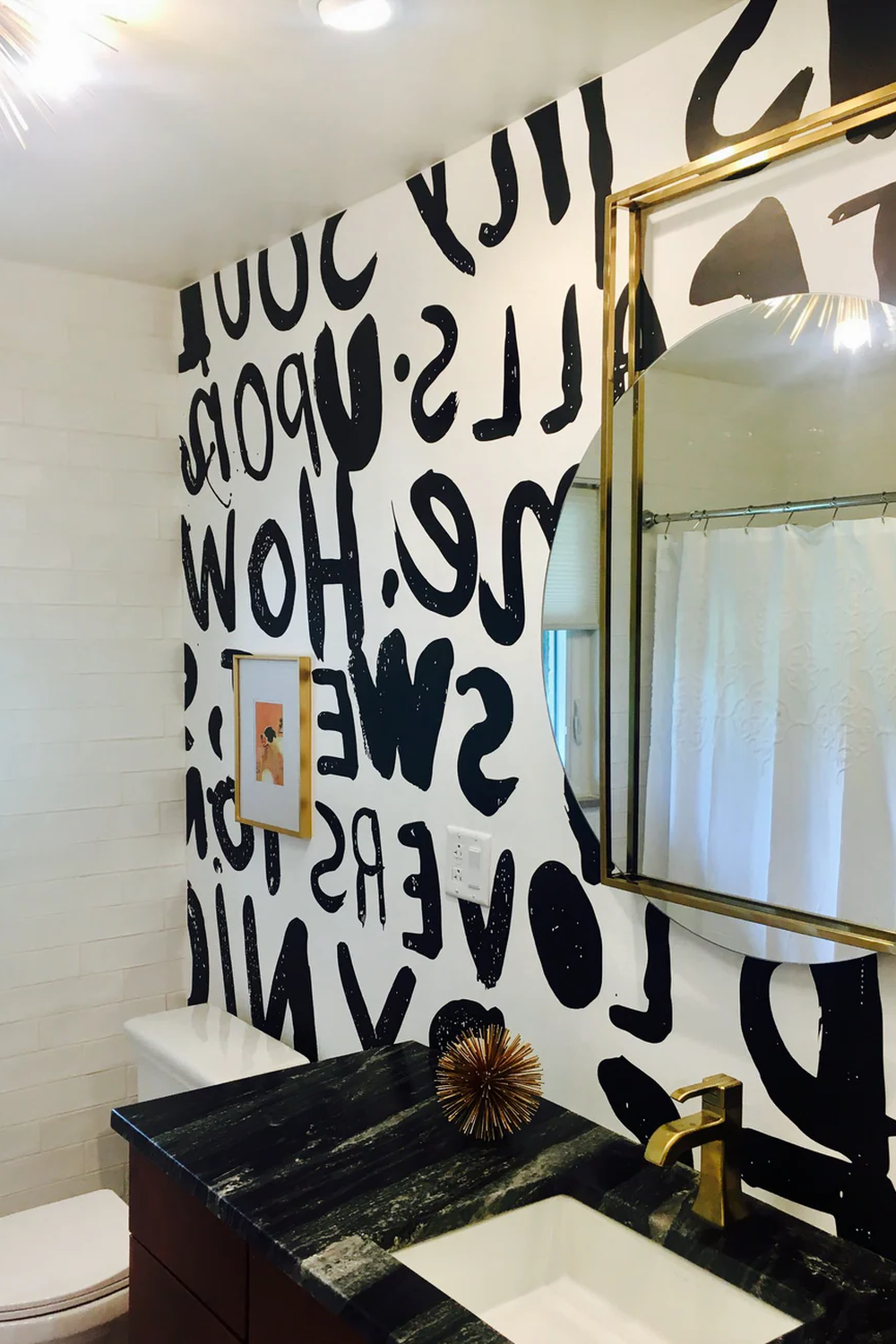 Baño moderno con pared de acento adornada con tipografía negra sobre fondo blanco