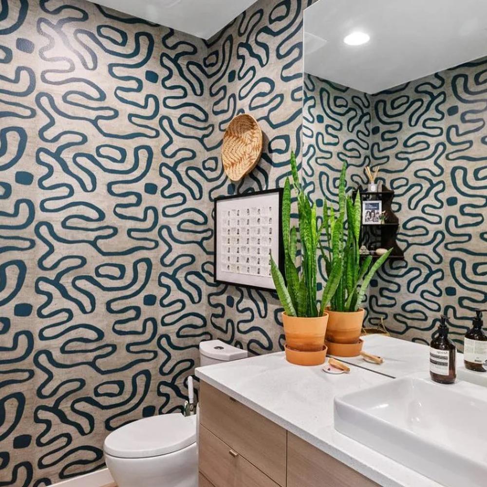 A bathroom featuring fluid abstract wallpaper with thick, wavy lines in deep teal against a neutral beige background.