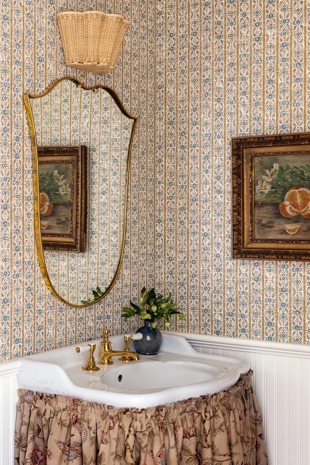 An elegant bathroom featuring vintage floral wallpaper with intricate designs in blue, beige and gold.