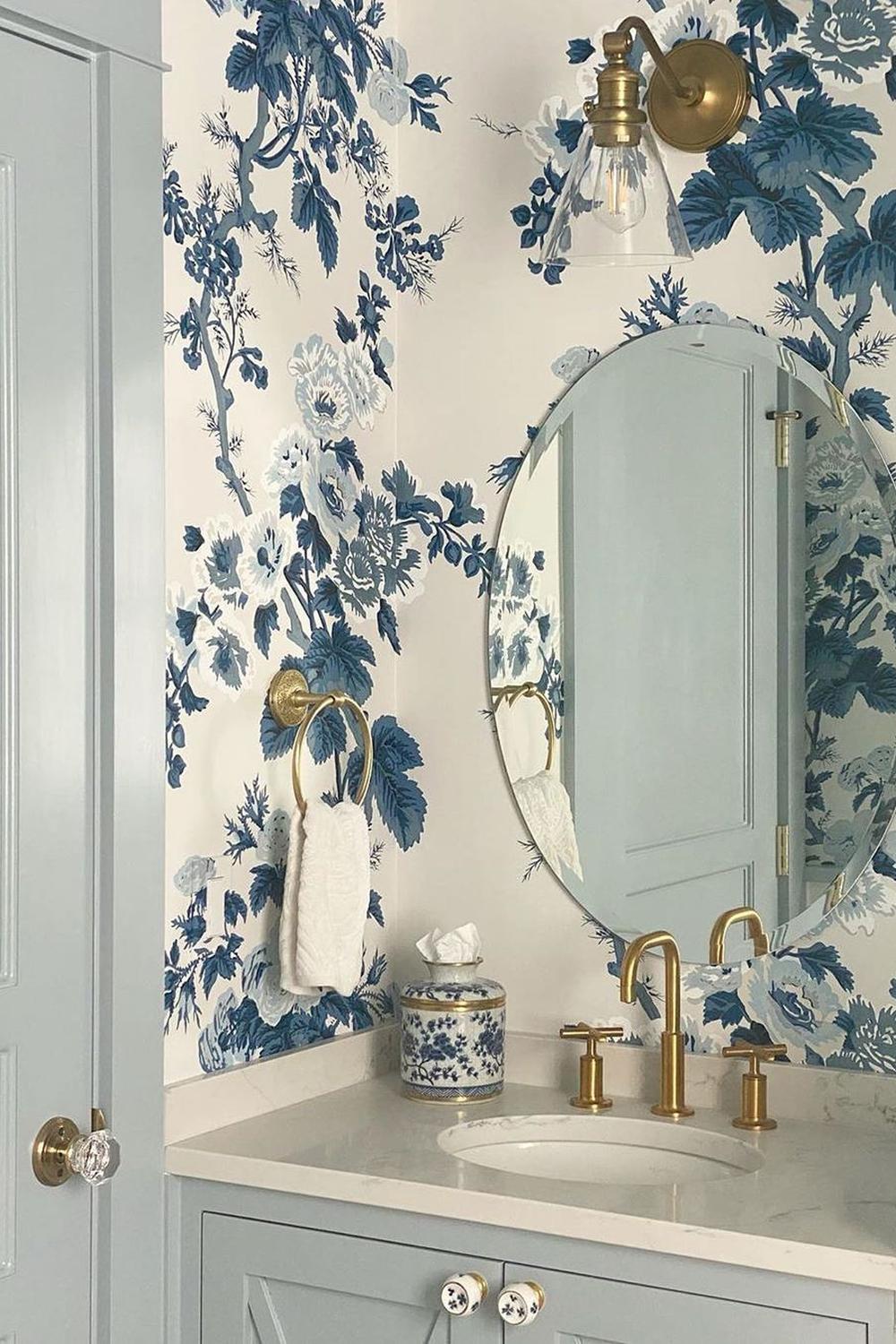 A stylish bathroom with creamy white wallpaper featuring detailed floral patterns in blue hues.