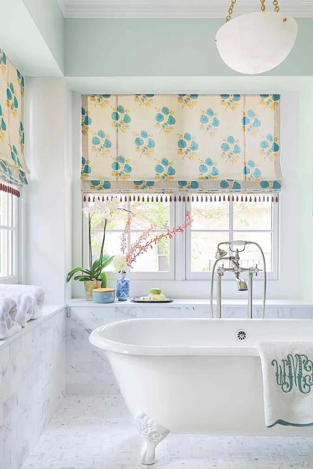 Floral Roman Shades for a Pop of Color - a bathroom featuring floral roman shades and a freestanding tub.