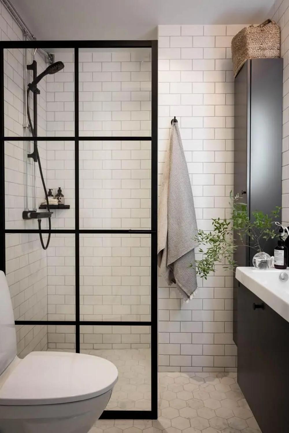 A contemporary bathroom showcasing black fixtures and white subway tiles with a glass shower enclosure.