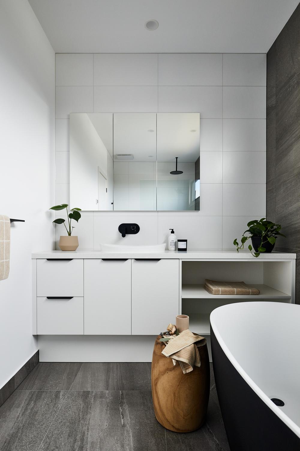 A minimalist bathroom featuring a freestanding bathtub and wall-mounted black faucet.