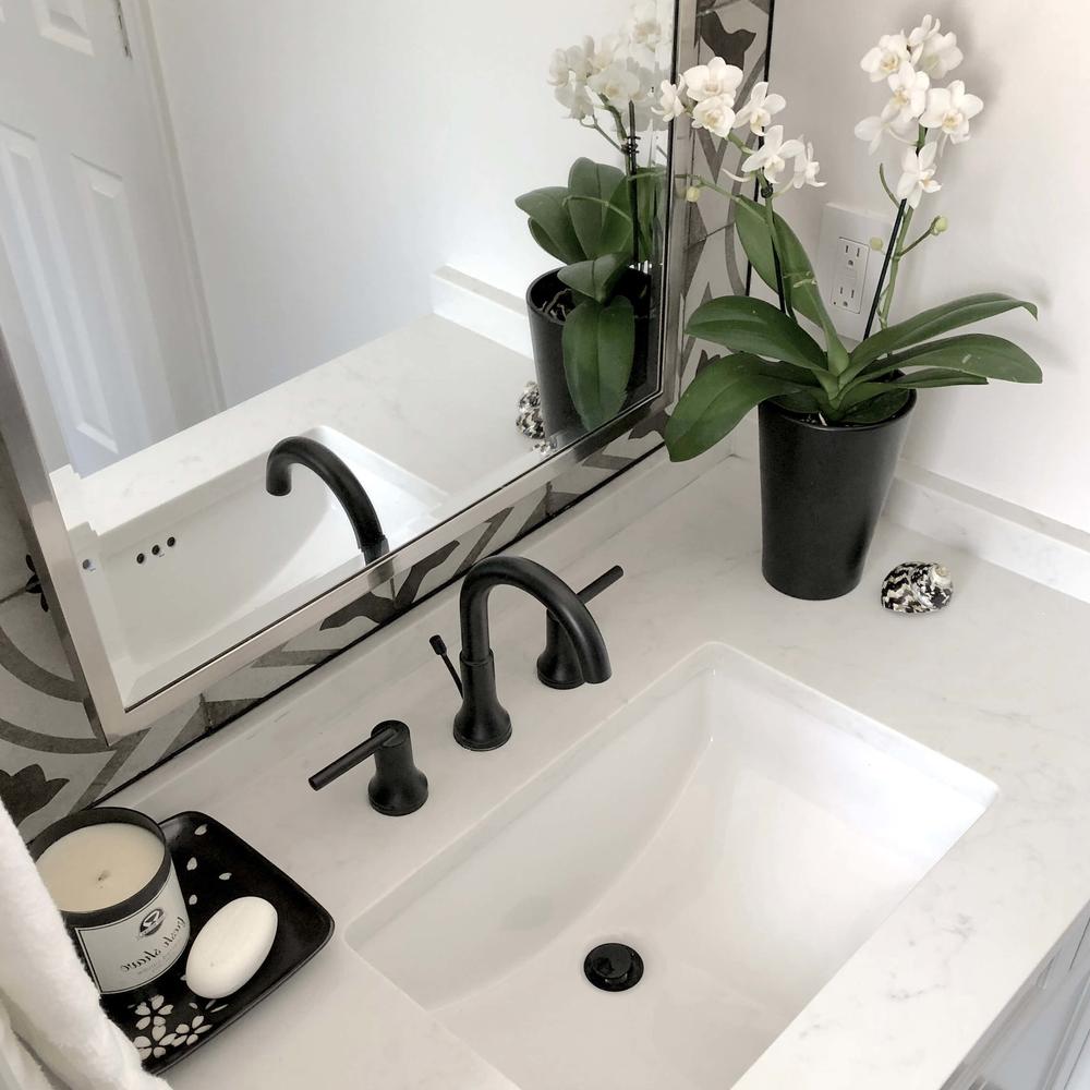 A bathroom featuring a stylish vanity with black fixtures and elegant decor.
