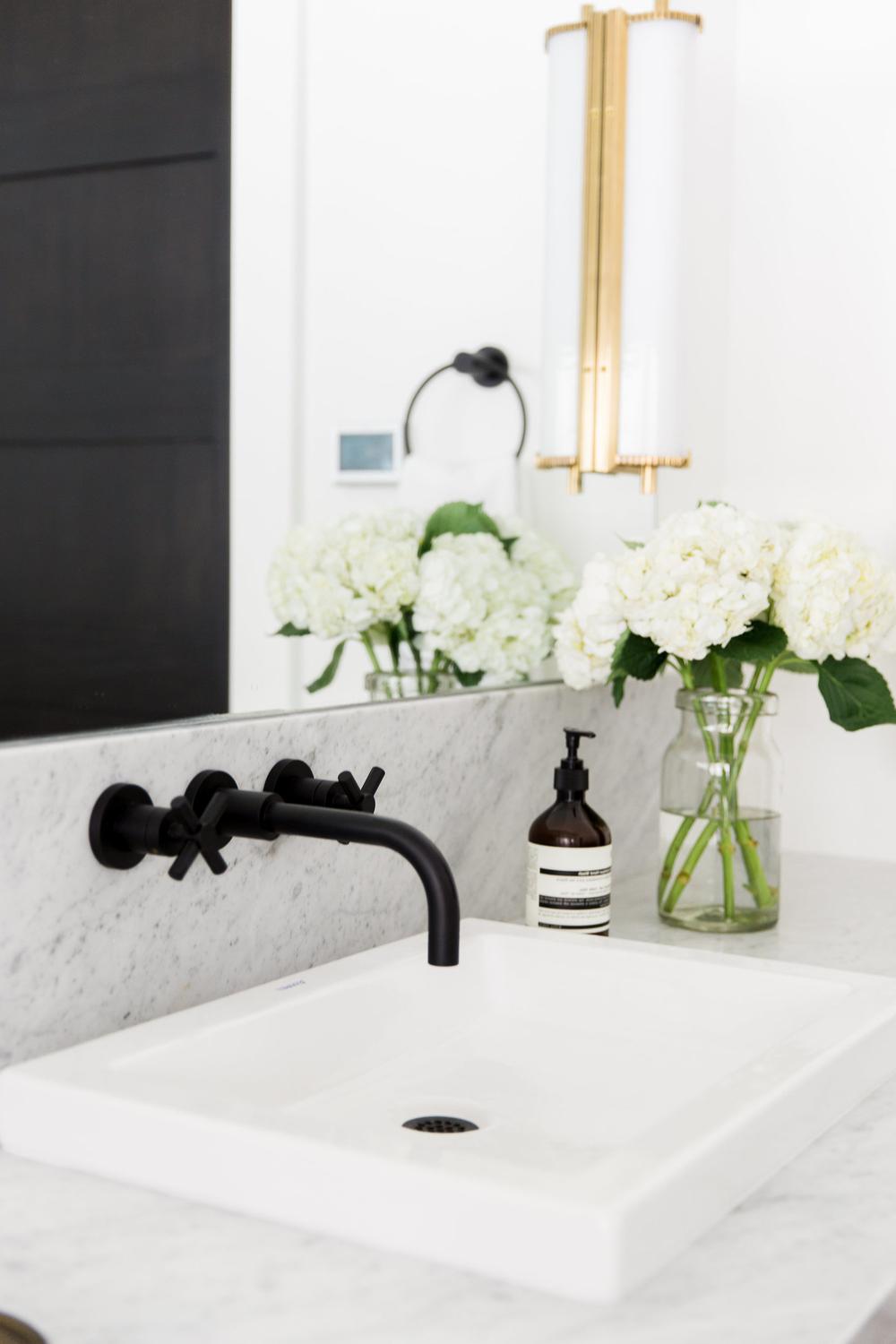 An elegant bathroom featuring black fixtures and a stylish marble countertop.