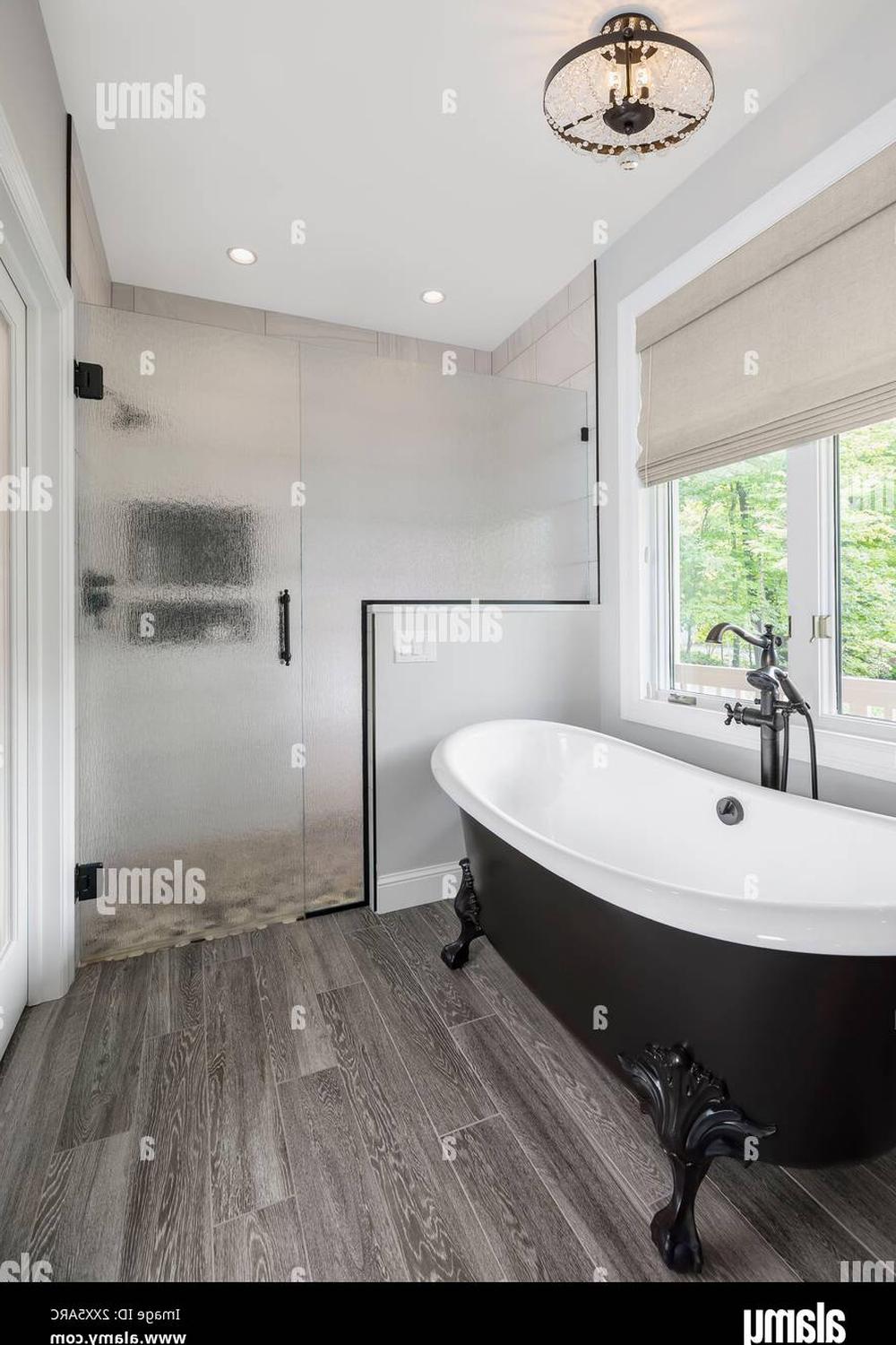 Modern bathroom design featuring a black and white clawfoot tub next to a frameless glass shower.