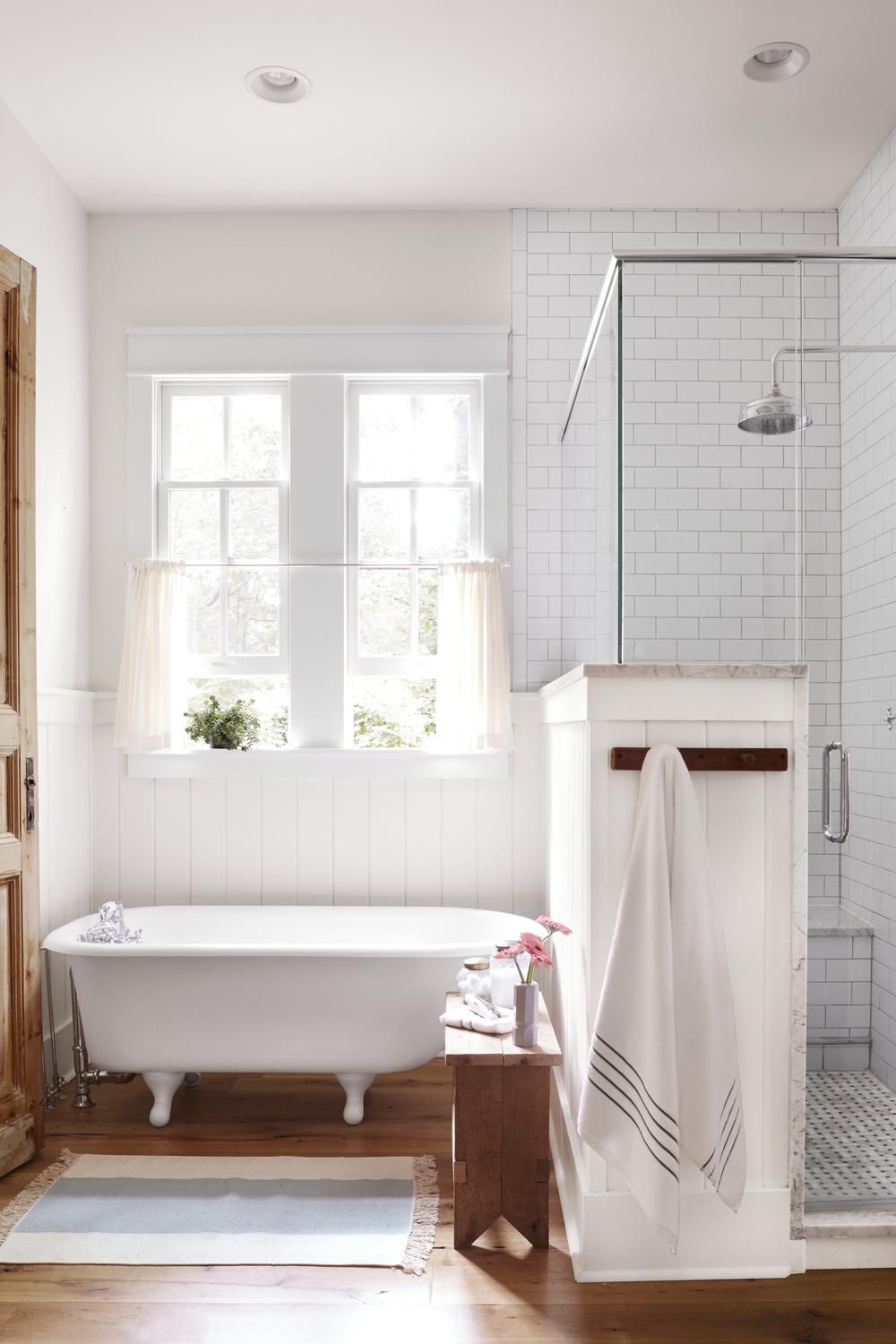 Airy bathroom featuring a white clawfoot tub and an elegant glass shower.