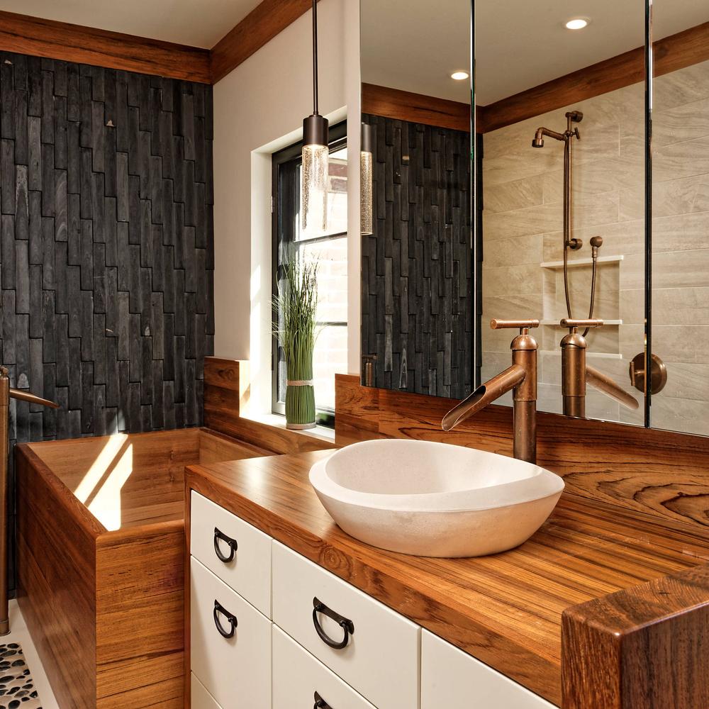 Baño moderno con pared negra y elementos de teak