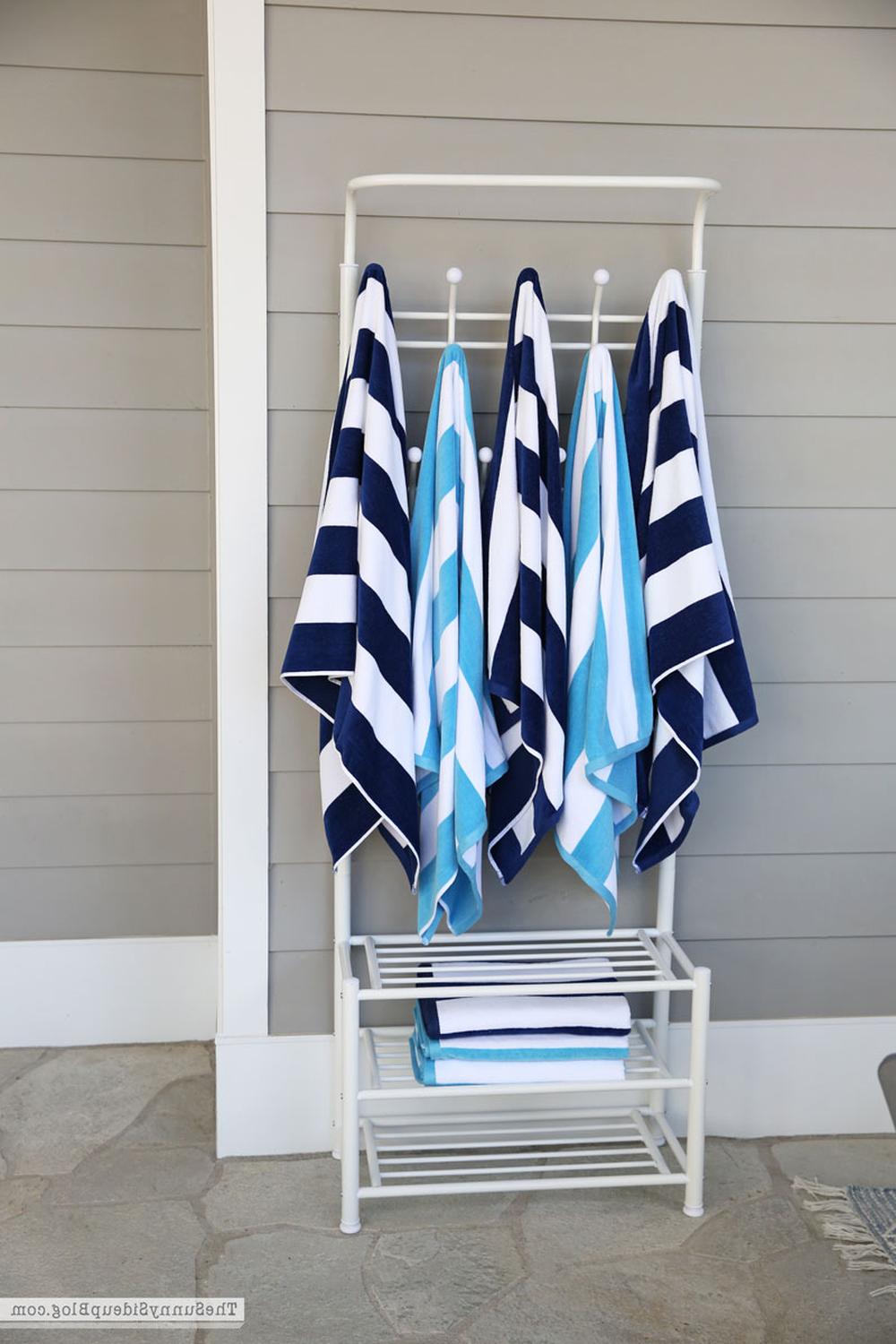 Stylish white three-tiered towel rack featuring a mix of patterned and solid towels in a modern bathroom