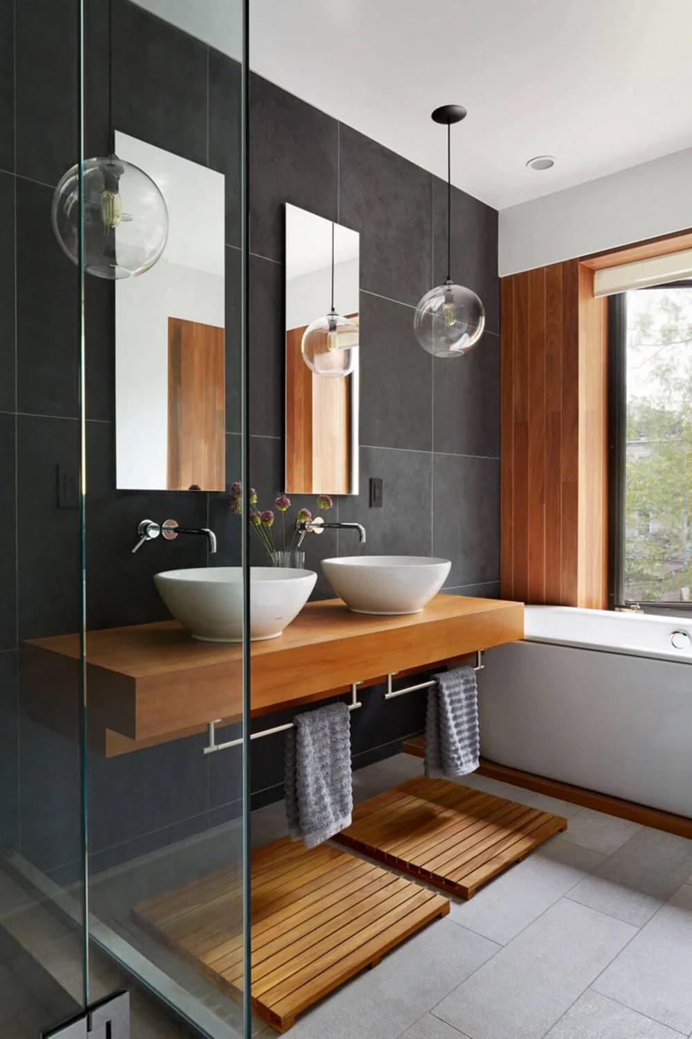 Modern bathroom featuring a spacious layout with dual vessel sinks over a warm wooden countertop.