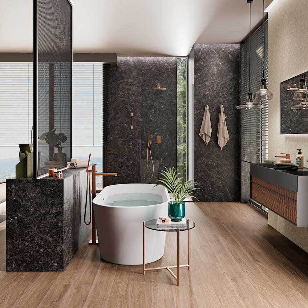 Beautiful bathroom design with a freestanding white bathtub, dark stone walls, and warm wooden flooring.