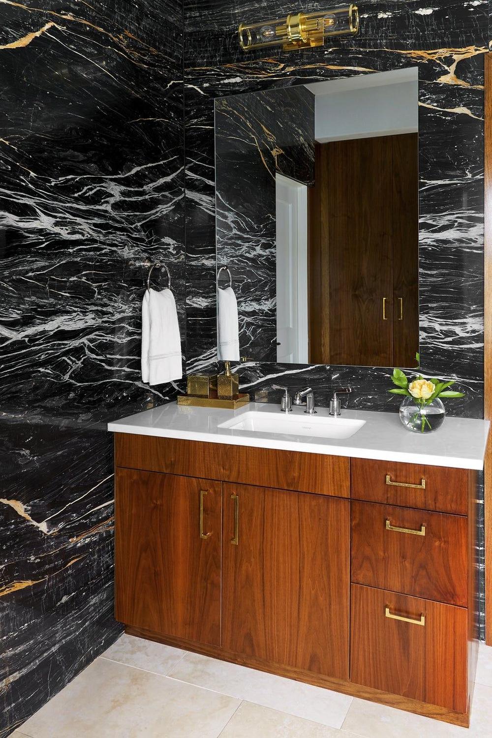 Luxurious bathroom design featuring dramatic black marble walls and a striking wooden vanity.