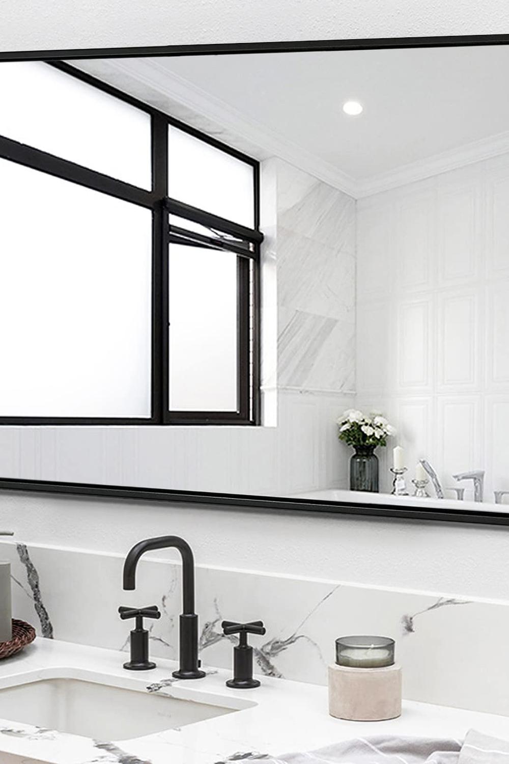 Modern bathroom with a sleek black-framed mirror and white marble countertop.