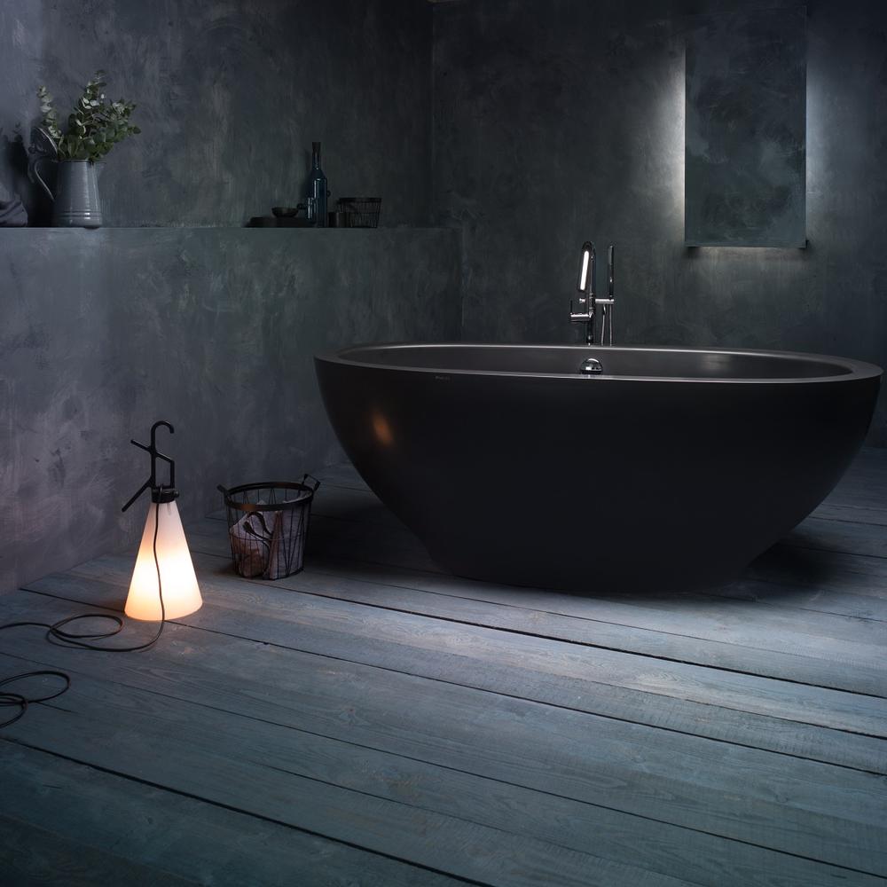 Minimalist bathroom featuring a rounded freestanding black bathtub and calming decor.