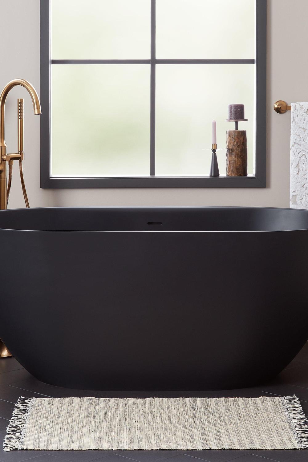Sleek bathroom featuring a black freestanding bathtub and industrial design touches.