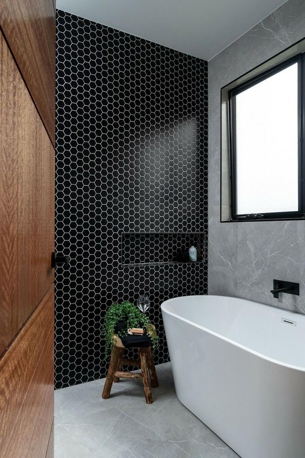 Baño contemporáneo con azulejos hexagonales negros y bañera
